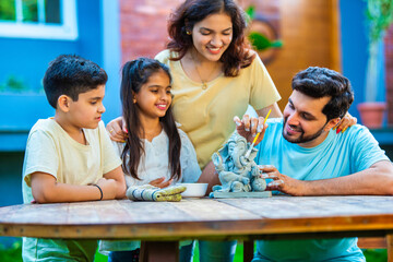 Indian family making eco-friendly Ganesh idol in outdoor garden for Ganesh Chaturthi celebration