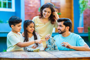 Indian family making eco-friendly Ganesh idol in outdoor garden for Ganesh Chaturthi celebration