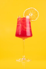 refreshing tropical strawberry red fruit cocktail glass with orange slice on yellow background