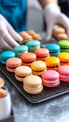 Fototapeta premium Hands Presenting Trays of Multicolored French Macarons on a Wire Cooling Rack., Bakery , Dessert