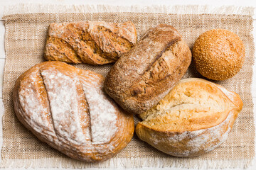 Assortment of freshly baked bread with napkin on rustic table top view. Healthy unleavened bread. French bread