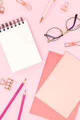 School supplies and eyeglasses on a pink background. Empty notepad.