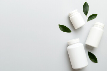 supplement pills with medicine bottle health care and medical top view. Vitamin tablets. Top view mockup bottle for pills and vitamins with green leaves, natural organic bio supplement, copy space