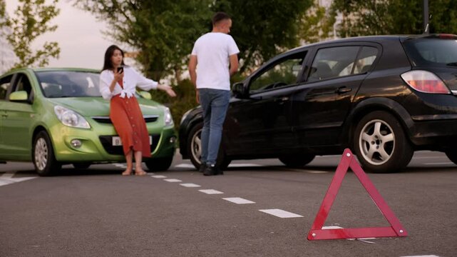 Red emergency stop triangle sign afore Destroyed car in car crash traffic accident on city road. Man driver looking on Smashed broken car in accident. Copy space.
