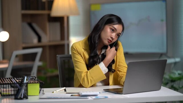Asian businesses women working in the office used laptop and smartphone at her dest 