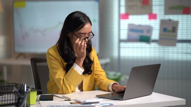 Asian businesses women working in the office used laptop and smartphone at her dest 