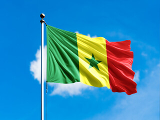 Senegal flag flying on blur blue clouds background.