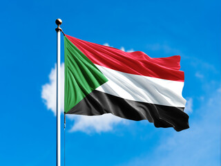 Sudan flag flying on blur blue clouds background.