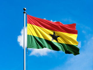 Ghana flag flying on blur blue clouds background.