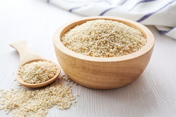 White Sesame Seeds in a wooden bowl with a wooden spoon on white background