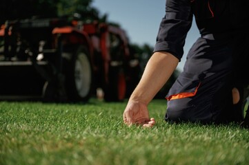 Quality control, touching the grass. Man is with utility tractor with grass cutter and aerator equipment on the field