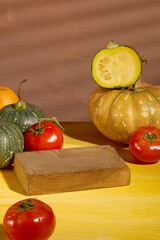 Empty wooden podiums decorated with some pumpkins and tomatoes placed on yellow table and brown background. Background for the presentation of food products with autumn concept.