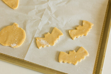 Unbaked Halloween-themed cookie dough shapes, including pumpkins