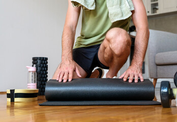 Male athlete rolls up yoga mat. Healthy and active lifestyle.