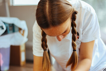 A girl with braided hair looks down.