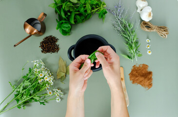 Overhead view of hands tearing bay leaves above a cauldron