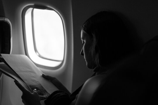 Woman reading magazine on airplane flight.