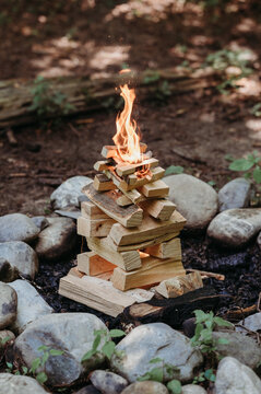 Small campfire with stacked wood burning in a forest setting