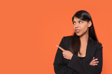 Confident Woman in Black Blazer With Orange Background Gestures Playfully in Creative Studio