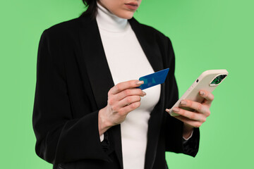 Elegant Woman Shopping Online With Smartphone and Credit Card Against a Green Backdrop