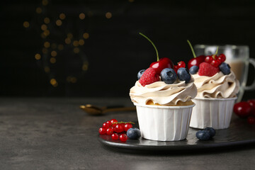 Tasty cupcakes with different berries on grey table, closeup. Space for text