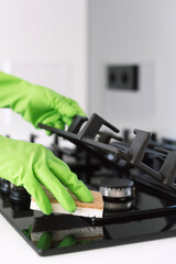 Woman cleaning a gas stove with sponge in a modern kitchen