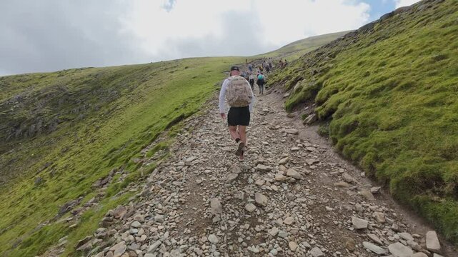 View of Snowdonia National Park, Wales. Man hiking to the peak of the mountain.
