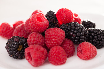 Handful of raspberry and blackberry berries on white background