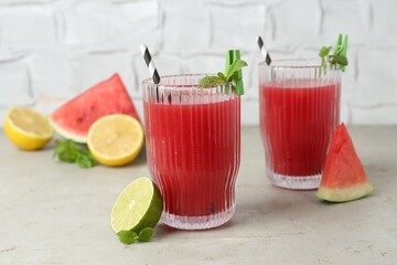 Delicious watermelon drink in glasses, fresh fruits and mint on light table