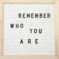 Letter board with phrase Remember who you are on white background, top view