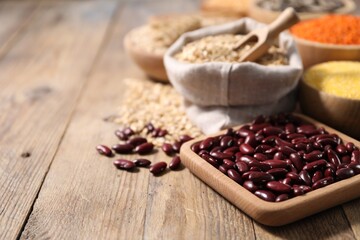 Different types of cereals and legumes on wooden table, closeup. Space for text