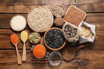 Different types of cereals, seeds and legumes on wooden table, flat lay