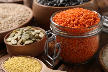 Different types of cereals, seeds and legumes on wooden table, closeup