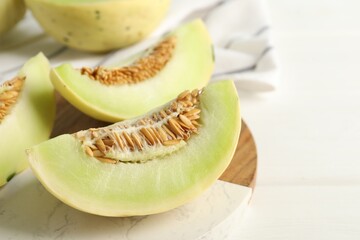 Fresh cut honeydew melon on white wooden table, closeup