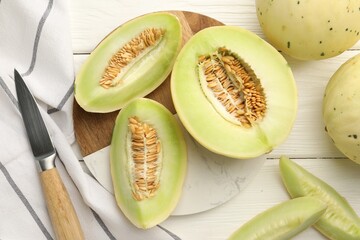 Fresh cut honeydew melons on white wooden table, flat lay