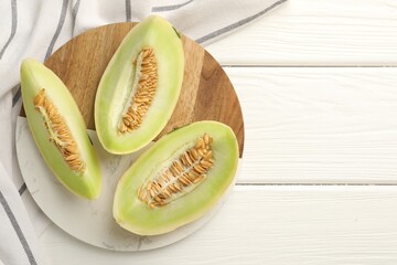 Fresh cut honeydew melon on white wooden table, top view. Space for text