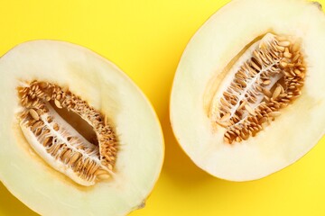 Halves of fresh melon on yellow background, top view