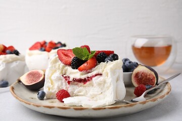 Pavlova cake (meringue dessert) with whipped cream, fresh berries, mint and fig on table, closeup