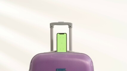 Smartphone with green screen is placed on purple suitcase.
