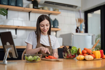 Young Woman Preparing a Healthy Salad in a Modern Kitchen with Fresh Vegetables and a Smile