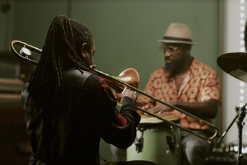 Fototapeta premium Black musician with long dreadlocks enjoying playing music on trombone in jazz band