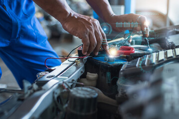 Close-up of a mechanic's hands working on an electric vehicle battery with digital interface overlays showing technical details.