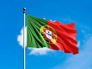 Flag of portugal waving on blurred blue cloud background.