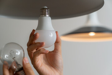 The young woman is replacing the incandescent bulb with an LED bulb