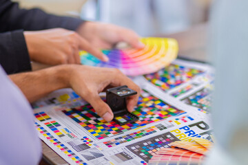 Worker checking print quality of media graphics proof print and color tone in printing industry....