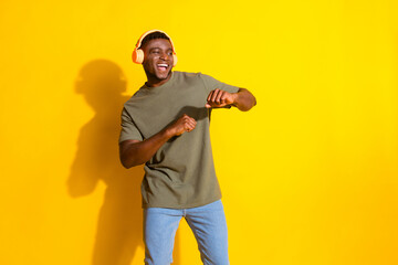 Photo of glad cheerful nice man wear stylish khaki clothes music dance empty space isolated on yellow color background