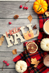 Autumn flat lay composition with Hello Fall sign, pumpkins, autumn decor, red scarf on wooden desk table. Top view.