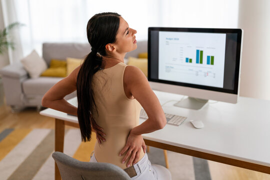 Tired woman worker sit at desk touch back suffer, woman strong backache, incorrect posture concept