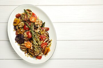 Delicious salad with grilled vegetables on white wooden table, top view. Space for text