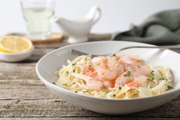 Delicious pasta with shrimps and cheese on wooden table, closeup